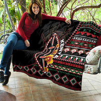 Black quilt draped on couch with tribal shield design, floral accents, and geometric border.