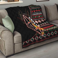 Black quilt on sofa with colorful tribal stripe pattern, shield graphic, and diamond trim.