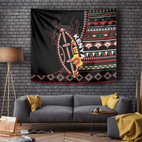 Black tapestry wall hanging with large shield, red/green pattern bands, and flower