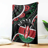 Black Kenya blanket hanging on floor with large “KENYA” graphic and red-white flower motif