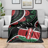 Black Kenya blanket spread on gray couch, red-green-white geometric pattern with “KENYA”