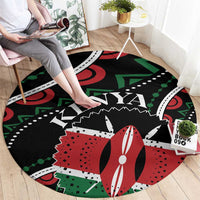 Round black rug with red, green, and white geometric pattern, shown from seated view