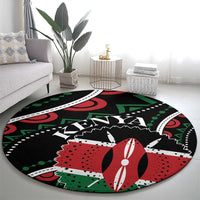 Round black area rug with bold red and green patterns and white detailing