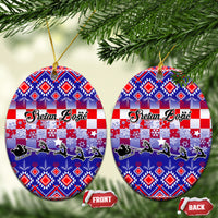 Two blue oval ceramic Christmas ornaments with Croatian embroidery pattern, gold loops.