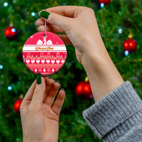 Red round ceramic Christmas ornament being held, white eagle and tree pattern, gold hanging loop