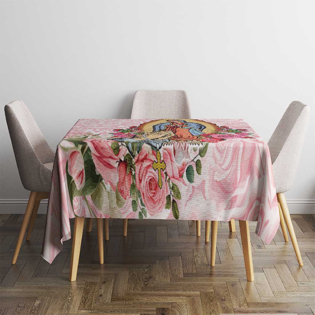 Pink floral tablecloth with central religious-style illustration and rose vine accents.