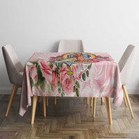 Pink floral tablecloth with central religious-style illustration and rose vine accents.