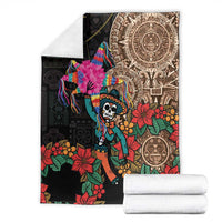 Black blanket with colorful skeleton and flowers, shown folded with white backup fabric rolls