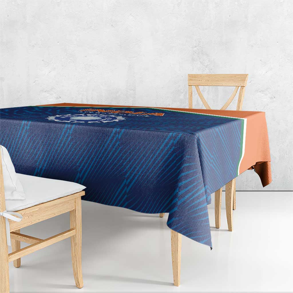 Blue India cricket tablecloth with orange edge stripe, overhanging on a wooden table