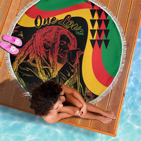 Round beach blanket with reggae lion artwork and white fringe edge on a wooden mat