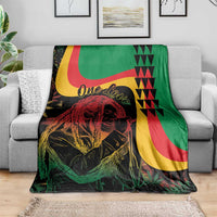 Reggae Marley throw blanket draped on a gray sofa, featuring One Love and lion portrait