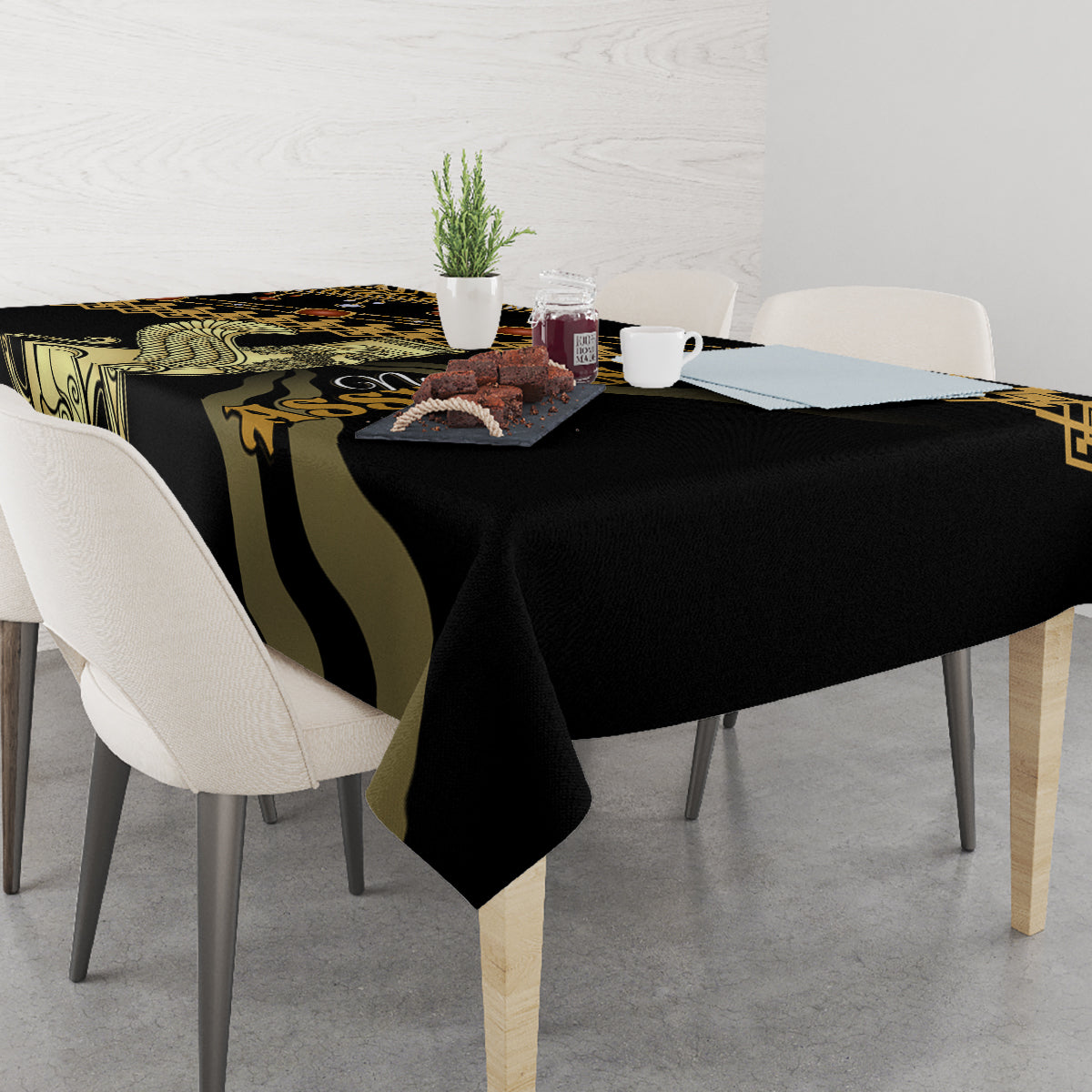 Black tablecloth with gold and green decorative print, covering dining table with plates