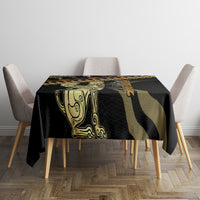 Black tablecloth with gold and green central figure motif and geometric stripes, on square table
