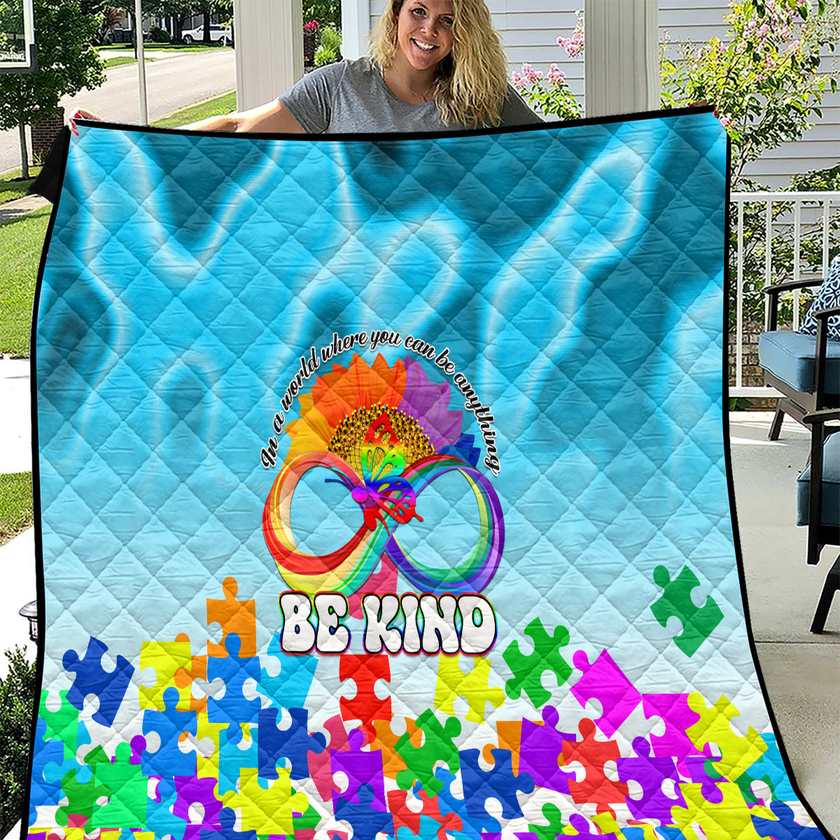 Blue quilt with diamond quilting, colorful puzzle pieces and “Be Kind” graphic