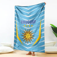 Uruguay football blanket hanging over bed, light blue chevrons with sun emblem and stars