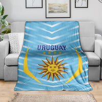 Uruguay football blanket draped on sofa, light blue chevrons with sun emblem and stars