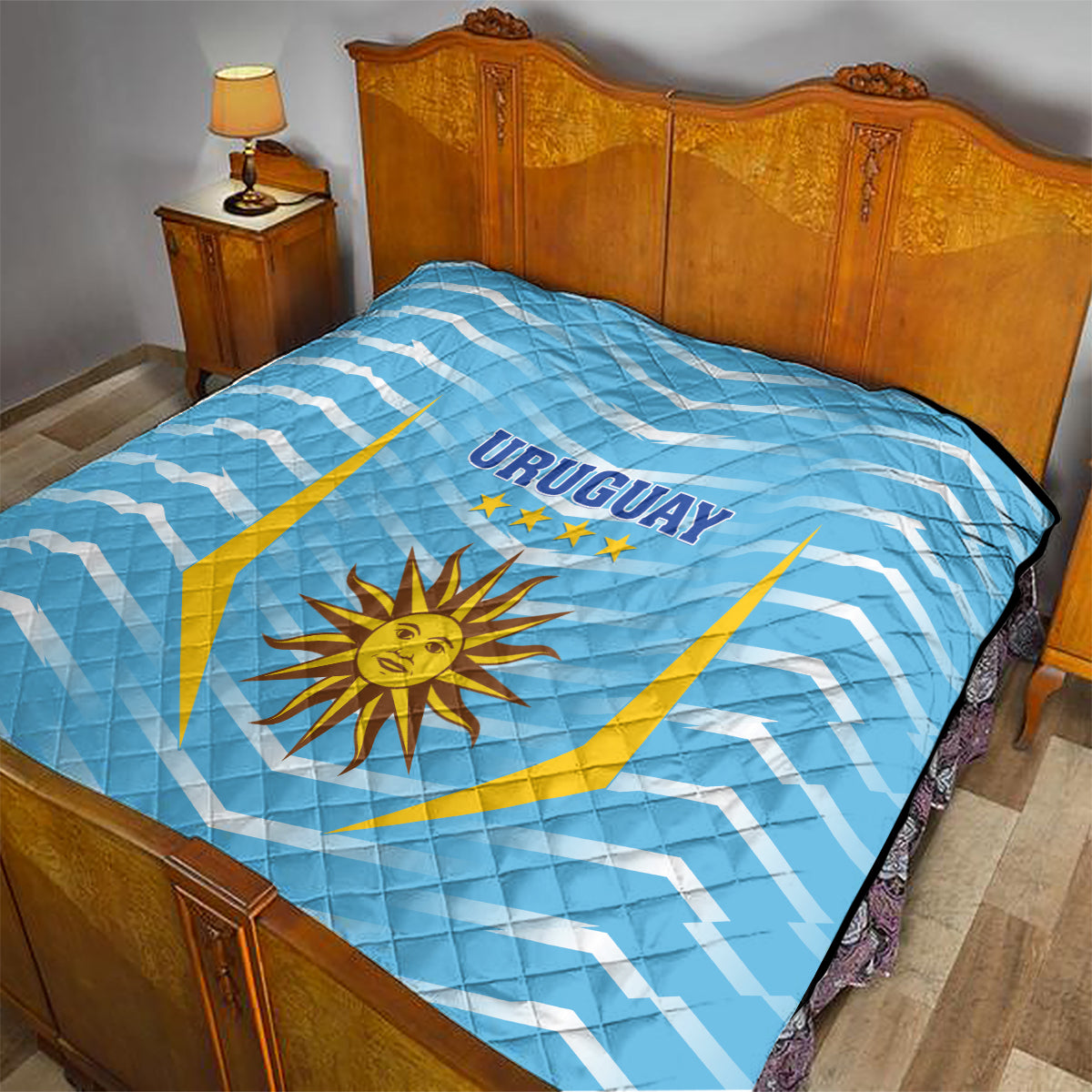 Light blue bed quilt with 'URUGUAY' text, sun emblem and gold shield lines