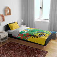 Bedding set on single bed: yellow pillowcases and green duvet with crest and red floral details
