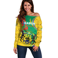Off-shoulder sweater in green and yellow with emblem text and lion print, long sleeves