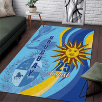 Blue rectangular rug with large golden sun, “25 August” text, and dark silhouette figures