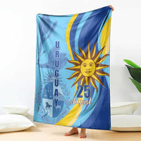 Blue Uruguay Independence Day blanket draped with sun "25 August" graphic and silhouettes