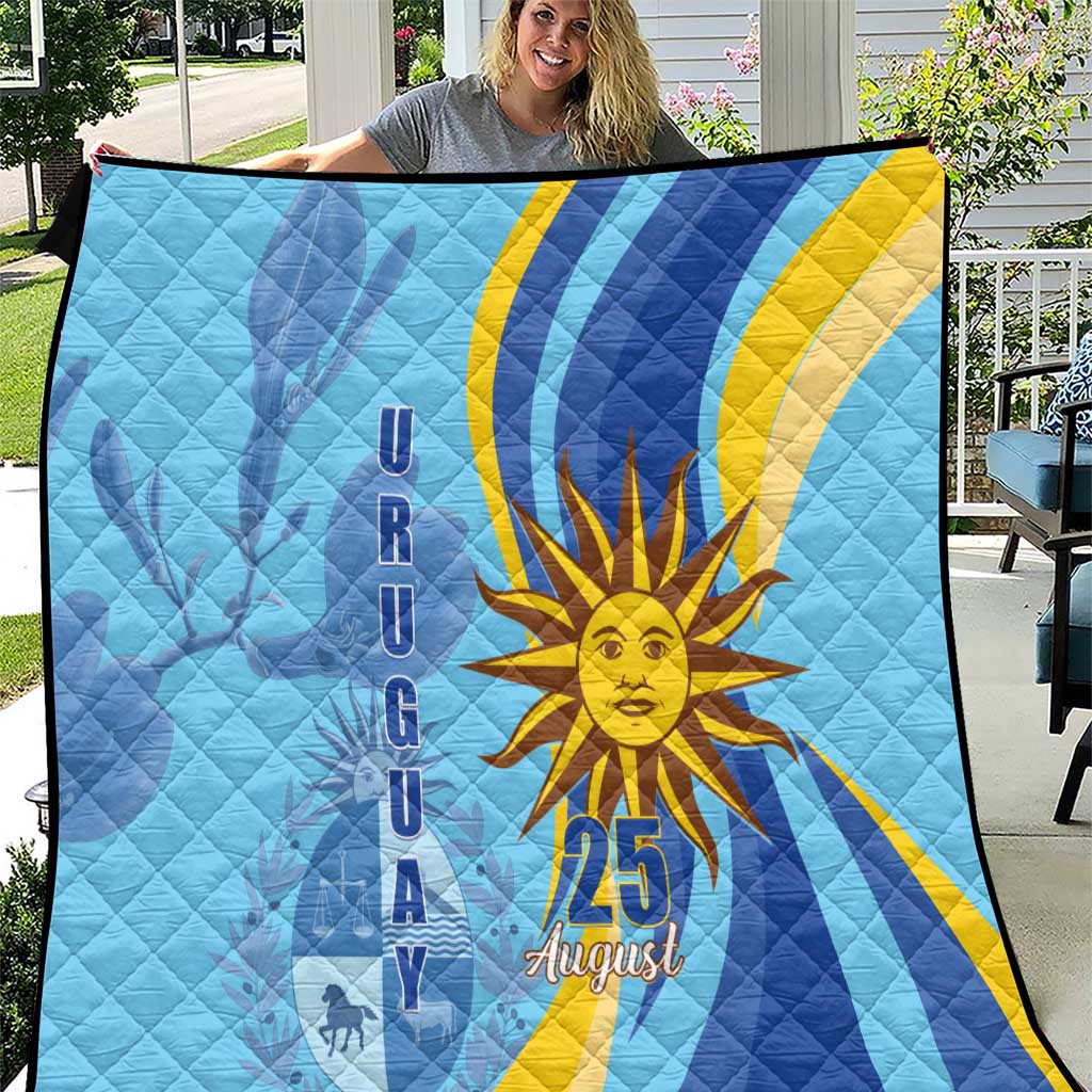 Light blue quilt held outdoors, featuring yellow sun, blue stripes, and “25 August”
