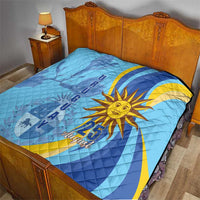 Light blue quilt on bed with yellow sun graphic, blue stripe accents, and “25 August”