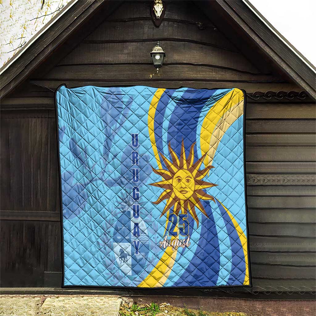 Light blue quilt hanging on wooden wall, showing yellow sun and “25 August”