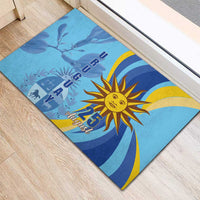 Blue rubber doormat with sun emblem and “25 August” design, corner view on wood floor