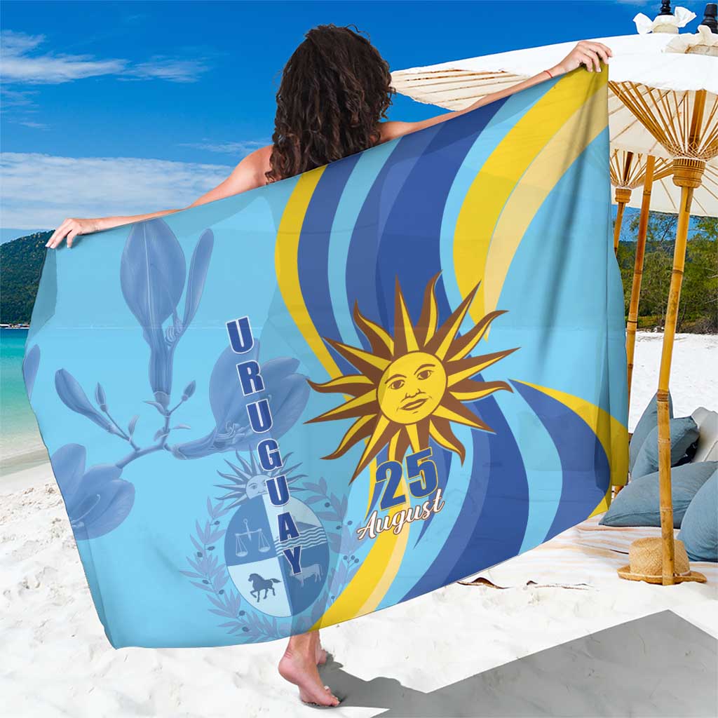 Blue Uruguay Independence Day sarong with sun and 25 August graphic, draped over shoulders.