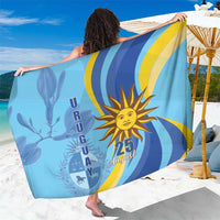 Blue Uruguay Independence Day sarong with sun and 25 August graphic, draped over shoulders.