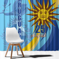 Blue window curtain with sun emblem and vertical “URUGUAY” lettering on a blue background.