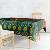 Green Christmas tablecloth with repeating geometric and floral motifs, draped over table