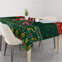 Green Christmas tablecloth spread across table with gold floral and zigzag pattern