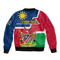 Blue, red, and green Namibia-style bomber jacket with sun-and-emblem graphic and “YOUR TEXT”