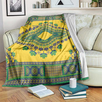 Yellow dashiki blanket with green and blue ornamental border, draped over bed.