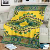 Yellow dashiki blanket with patterned border and central green oval medallion on couch.