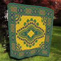 Yellow quilt with teal border print and centered diamond emblem with leaf details