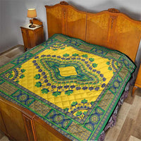 Yellow quilt laid on a bed with teal-green patterned border and central motif