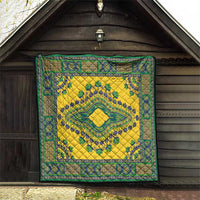 Yellow quilt hanging on a wooden wall with teal-green ornate frame and medallion