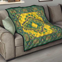 Yellow quilt draped over a sofa with teal-green border and central emblem pattern