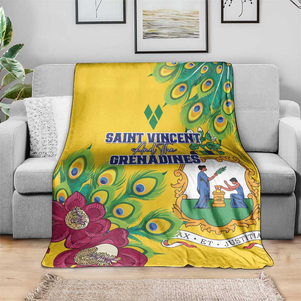 Yellow blanket laid on a gray couch, featuring peacock feather print and large magenta flowers