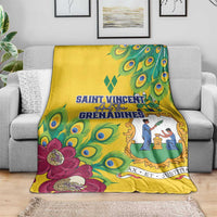 Yellow blanket laid on a gray couch, featuring peacock feather print and large magenta flowers