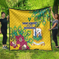 Yellow quilt spread on grass, peacock feather design with floral bouquet and emblem