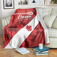 Red and white Canada flag blanket with Canada logo and maple leaves, draped on couch