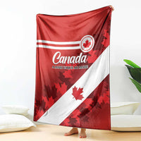 Red and white Canada flag blanket with maple leaf emblem, shown raised on living room floor
