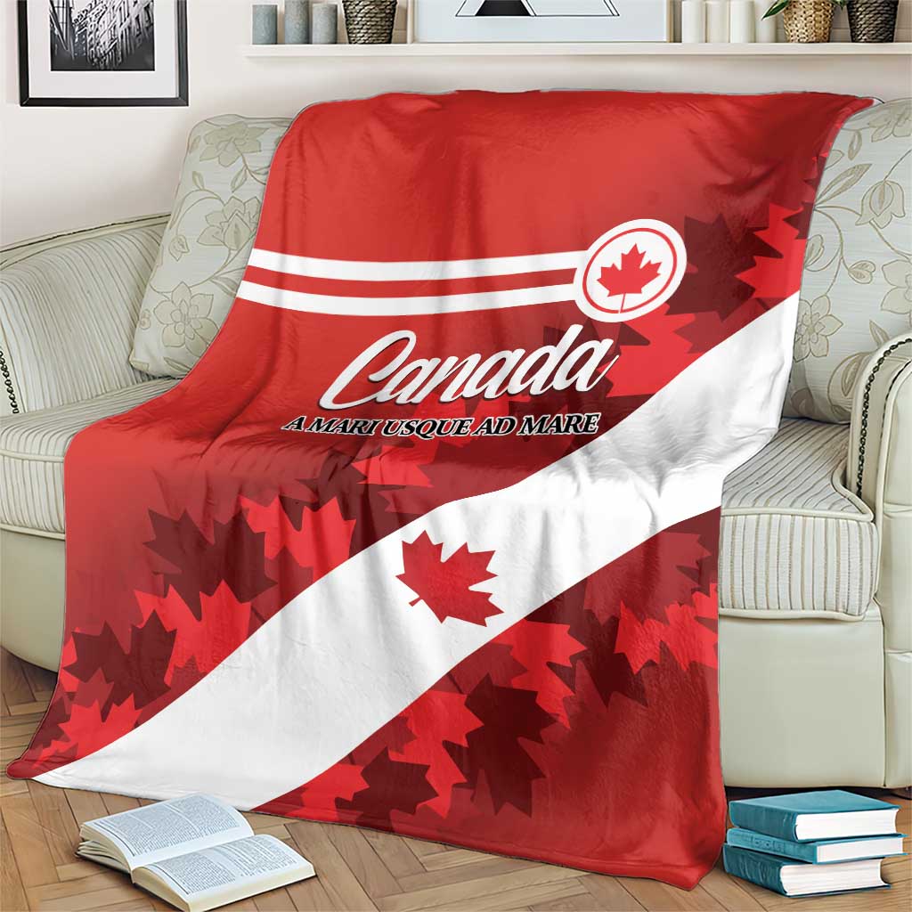 Red and white Canada flag blanket with Canada text and maple leaves, laid over couch arm