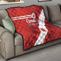 Red Canada quilt folded on sofa, white diagonal stripe and maple leaf pattern