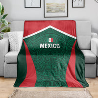 Mexico football blanket folded over gray couch, green emblem with red trim and Mexico text