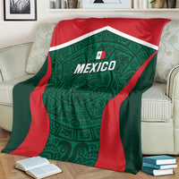 Mexico football blanket draped over cream sofa, green emblem with red border and Mexico lettering